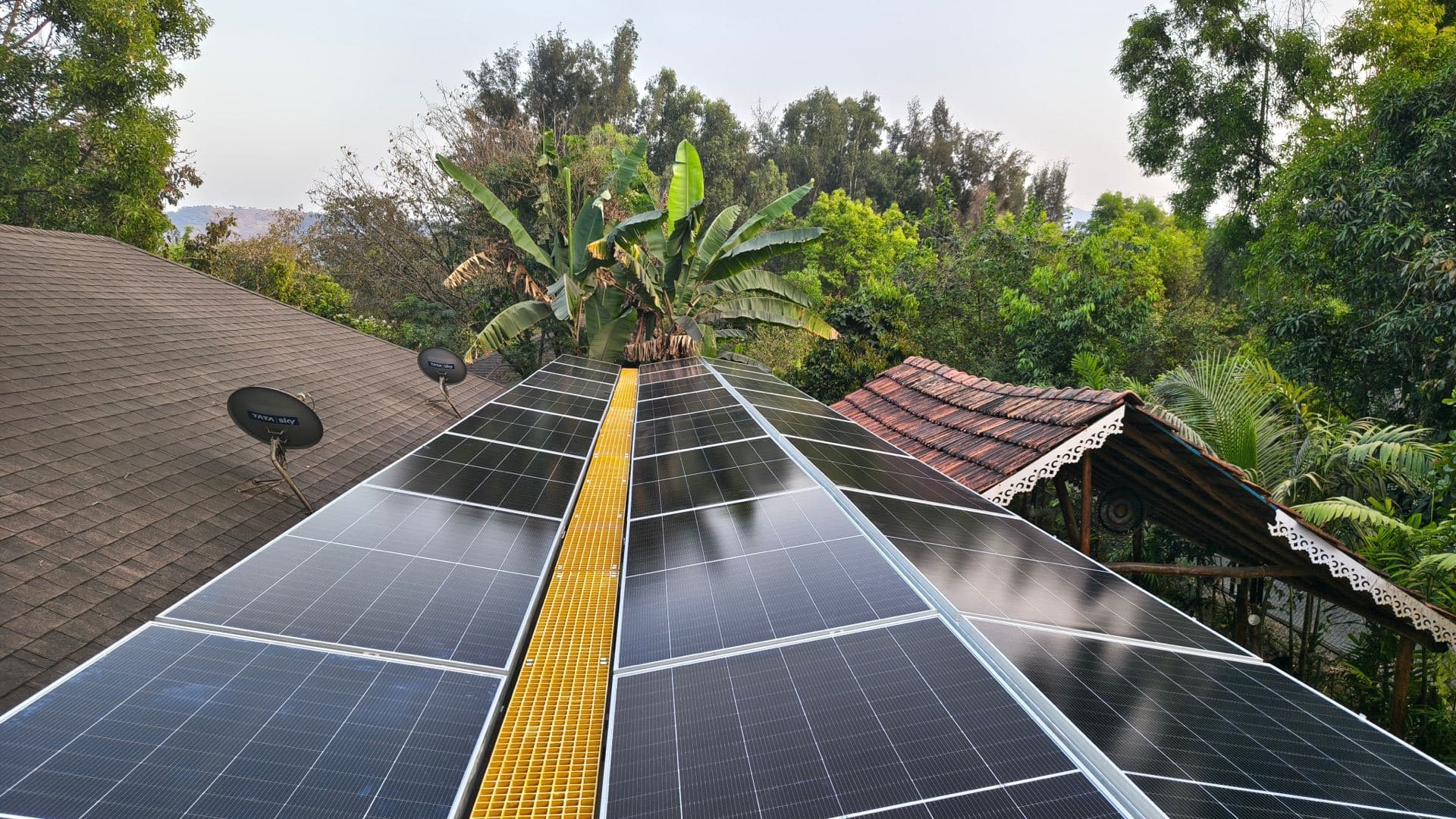 Rooftop solar panels at sunset with the Pune skyline behind