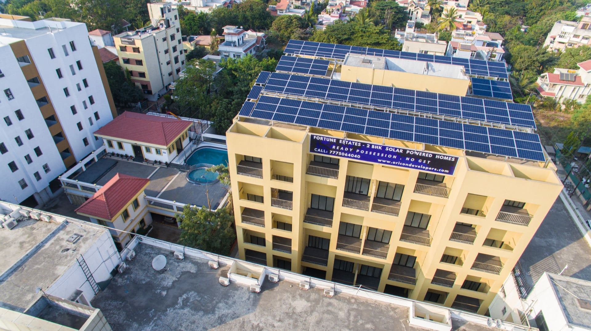 Aerial view of a residential building in Pune with its full rooftop covered in solar panels